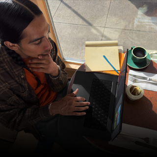 Afbeelding van iemand die in een koffietentje zit te werken op een MacBook Pro die niet op netstroom is aangesloten